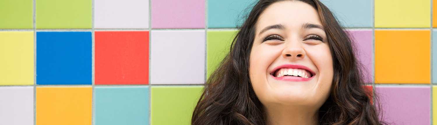 A woman smiling in front of a colourful background